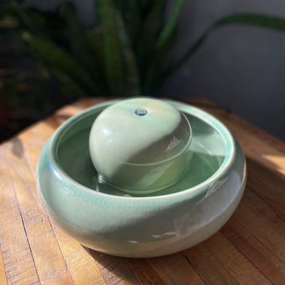 Feng Shui Zimmerbrunnen Mint auf Holztisch mit Pflanze im Hintergrund

Feng Shui Wasserbrunnen Mint im Wohnzimmer neben Sofa

Feng Shui Brunnen Mint im Garten mit Vogel am Wasser